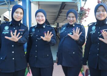 ANGGOTA polis wanita menunjukkan jari yang dicelup dakwat selepas mengundi awal di PPM Wilayah Dua, Johor Bahru.