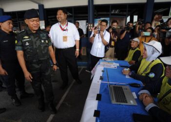KAMARUL ZAMAN MAMAT beramah mesra dengan petugas SPR ketika meninjau proses pengundian awal Parlimen Pulai di Markas PPM  Wilayah Dua, Johor Bahru.