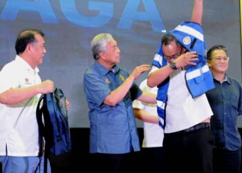 AHMAD ZAHID HAMIDI memakaikan jaket kepada salah seorang ketua kampung sempena Program Madani Siaga Peringkat Negeri Johor di PPR Melana Indah, Perling Johor Bahru.