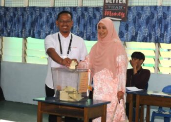 SUHAIZAN KAYAT dan isteri, Dr. Norsham Idris memasukkan kertas undi ke dalam peti undi  di SK Seri Melati, Johor Bahru.