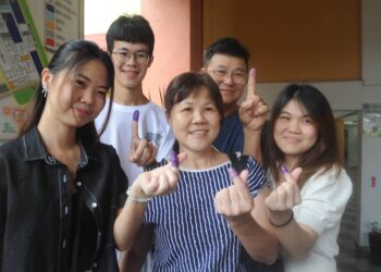LIEW YOKE SIANG (tengah) dan suaminya, Toh Kai Peet (dua dari kanan) serta tiga anak mereka,  Toh Wan Bin (kanan), Toh Jun Wei (dua dari kiri) dan Toh Wan Teng (kiri) menunjukkan jari yang dicalit dakwa selesai mengundi pada PRK Parlimen Pulai di SMK Taman Bukit Indah, Johor Bahru.