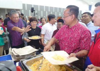 SUHAIZAN KAYAT (kanan) mengambil makanan untuk orang ramai yang menghadiri Majlis Kesyukuran Rakyat dan Petugas PRK PH dan BN di Taman Bukit Indah, Johor Bahru.