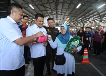 ZAHARI SARIP menyampaikan beras tempatan seberat 10 kg  dan seekor ayam yang dibeli oleh seorang pengunjung  sempena Program Jualan Agro Madani di Pasar Tani Kekal, Jalan Datin Halimah, Larkin Johor Bahru.