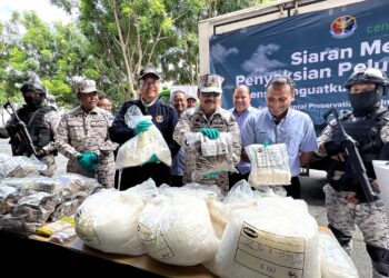 KHAIRUL Anwar Bachok (baris hadapan, empat dari kanan) menunjukkan pelbagai jenis dadah seberat 1,301kg yang bernilai RM27 juta yang akan dilupuskan di Pusat Kualiti Alam, Port Dickson.- UTUSAN/ZAKKINA WATI AHMAD TARMIZI.