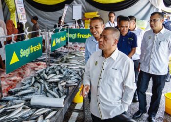 SAARANI Mohamad meninjau gerai jualan pada Program Mesra Hari Bertemu Pelanggan di Tanjung Malim hari ini. - UTUSAN