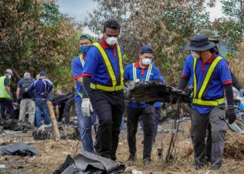 PETUGAS mengutip serpihan pesawat di lokasi nahas pesawat terhempas di Lebuhraya Guthrie berdekatan Bandar Elmina. - UTUSAN/FARIZ RUSADIO