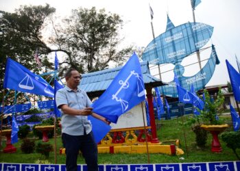 SEORANG lelaki memacakkan bendera Barisan Nasional (BN) berlatarbelakangkan wau gergasi Perikatan Nasional (PN) sempena kempen Pilihan Raya Kecil Dewan Undangan Negeri Pelangai di Felda Kemasul, Bentong.–  mingguan/SHAIKH AHMAD RAZIF