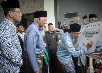 ANWAR Ibrahim menandatangani plak majlis penghantaran tiga kontena al-Quran sempena Solidariti Wakaf Sejuta Naskhah Al-Quran di Kompleks Nasyrul Quran, Presint 15, Putrajaya, hari ini. - FOTO/FAIZ ALIF ZUBIR
