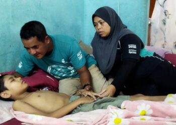 MUHAMMAD Qaish di sisi bapanya, Ahmad Mohamad Zain dan ibunya, Hasmah Ahmad ketika ditemui di rumah mereka di Kampung Charuk Bemban, Kupang di Baling. -UTUSAN/NORLIA RAMLI