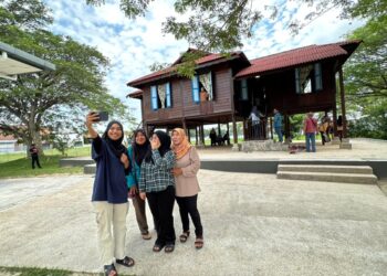 PENGUNJUNG  bergambar di replika rumah Lat ketika berkunjung Galeri Rumah Lat di Batu Gajah. - UTUSAN/LIYANA RAMLI