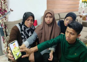 AHMAD Harraz Muhammad Noh (kanan) bersama ibunya, Maniliza Abdul Hamid (kiri) menunjukkan gambar arwah Muhammad Noh Muhammad Isa ketika ditemui di Jiboi, Seremban hari ini.-UTUSAN/NOR AINNA HAMZAH.