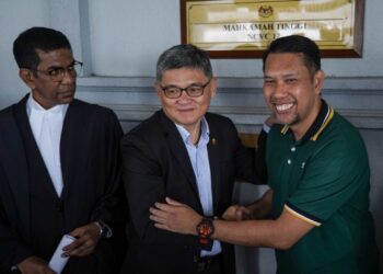 KENNY Goh Chee Keong (kiri) bersalaman dengan Muhammad Roslin Hashim di Mahkamah Tinggi Kuala Lumpur selepas kes mereka selesai secara baik. -  UTUSAN/AMIR KHALID