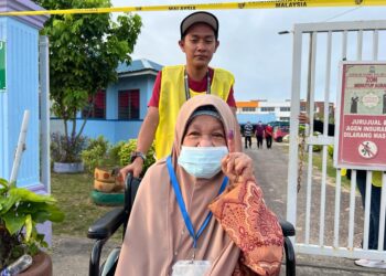 SALMAH Amir dibantu petugas SPR ketika hadir mengundi di Sekolah Agama (SA) Tun Dr. Ismail, Muar, Johor. - UTUSAN/ADNAN IBRAHIM