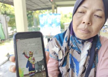 KAMISAH Abu Bakar menunjukkan gambar Muhammad Shaheizy Iman yang berjaya memenangi tempat pertama dalam pertandingan pakaian terbaik sempena sambutan Hari Kebangsaan Ke-66 peringkat Pasti Al Hasan, Taman Desa Port Dickson.-UTUSAN/NOR AINNA HAMZAH.