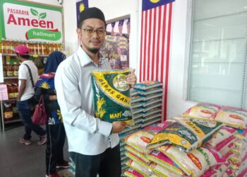 MOHD. Khairul Nizam Mohd. Razali menunjukkan Beras Ganu yang dipasarkan di Pasaraya Ameen Hallmart, Losong, Kuala Terengganu. 
– UTUSAN/TENGKU DANISH BAHRI TENGKU YUSOF