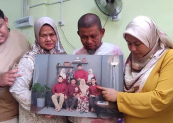 AHLI keluarga Allahyarham Muhamad Hafiz Muhamad Salleh menunjukkan gambar kenangan mereka sekeluarga di Sungai Petani.