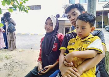 MUHAMMAD Amirul Ikhwan Ridzuan bersama dua daripada tiga adiknya, Nurin Alya Iwanie (kanan) dan Muhammad Ridz Danial ketika menunggu jenazah ibu bapa mereka di Unit Forensik HSAH, Sungai Petani.