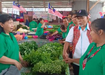 HASSAN Abdul Karim (kanan) menyantuni peniaga-peniaga di Pasar Borneo Johor sempena Sambutan Hari Malaysia, hari ini.