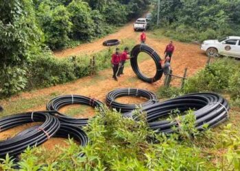 ANGGOTA Jabatan Amal Malaysia (JAM) dan penduduk bergotong-royong memasang paip poly ke rumah penduduk di Kampung Kembir, Ulu Tembeling di Jerantut, Pahang. – UTUSAN/HARIS FADILAH AHMAD