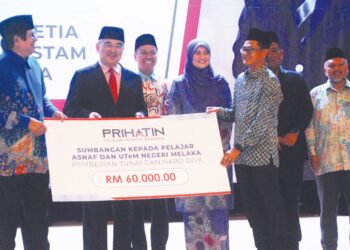 MOHD. ALI Mohd. Rustam menyampaikan replika cek berjumlah RM60,000 daripada Prihatin di Dewan Canselor UTeM, Durian Tunggal, Melaka. – UTUSAN/AMRAN MULUP