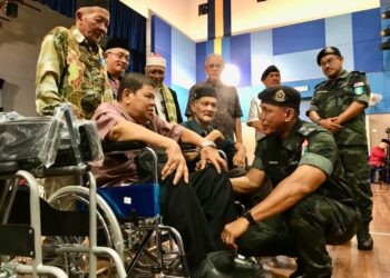 SHEIK Azahar Sheik Omar (duduk kanan) bermah mesra dengan pesara yang menerima bantuan kerusi roda di Markas Batalion 8 PGA Pengkalan Chepa, Kota Bharu, Kelantan hari ini.-UTUSAN/ ROSLIZA MOHAMED