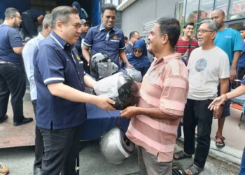 ANTHONY Loke Siew Fook menyampaikan topi keledar kepada orang ramai pada Program Tukar Helmet anjuran JPJ di Nilai, Seremban hari ini.