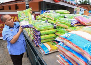 KAKITANGAN Pertubuhan Peladang Kawasan Kangkong menyusun bekalan beras untuk dijual di kedai mereka di Kangkong, Pasir Mas, Kelantan.-UTUSAN/KAMARUL BISMI KAMARUZAMAN.