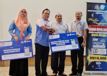 MOHD. NAWARDI Saad menyampaikan replika cek berjumlah RM10,000 kepada wakil Persatuan Penduduk Taman Penghulu Jabar Bukit Katil di Kompleks KDN, Ayer Keroh, Melaka. - UTUSAN/AMRAN MULUP