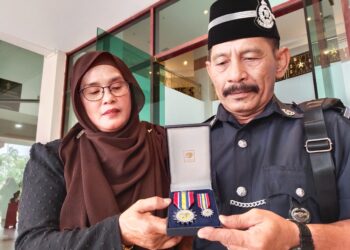 SAZALI Shaari (kanan) menunjukkan PJPN kepada isteri, Noraini Zakaria pada Majlis Istiadat Penganugerahan PJPN di Seri Negeri, Ayer Keroh, Melaka. - UTUSAN/MUHAMMAD SHAHIZAM TAZALI