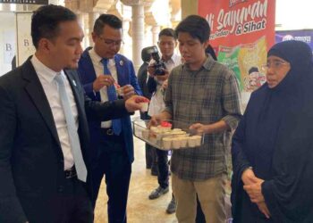 Onn Hafiz (kiri) mencuba salah satu produk yang dipamerkan usahawan di Mini Karnival Maju Johor yang diadakan di Kota Iskandar, Iskandar Puteri, hari ini.