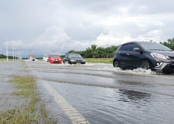 KENDERAAN melalui jalan yang dinaiki air di Kilometer 15, Jalan Selama-Alor Pongsu di Bagan Serai. - UTUSAN/WAT KAMAL ABAS