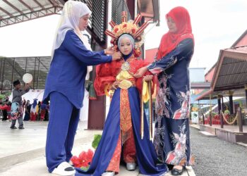HASNI Fazlina Hassan, (kiri) menyiapkan anaknya dengan pakaian bertemakan gabungan tradisional, Tionghoa dan puteri Perak sempena majlis penutup bulan Kebangsaan peringkat Sekolah Tengku Budriah (STB), Arau, Perlis semalam. – UTUSAN/MOHD. HAFIZ ABD. MUTALIB