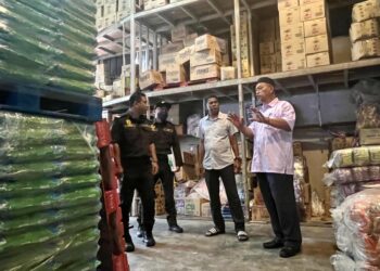 RAZALI Saad (kanan) meninjau keadaan bekalan beras putih tempatan di salah sebuah kedai pemborong sekitar Perlis.- UTUSAN/ASYRAF MUHAMMAD
