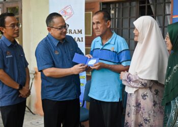 ZAMRI Misman (dua, kiri) menyerahkan dokumen kad pengenalan kepada warga emas, Abdul Wahab Saleh (tengah) pada Program Menyemai Kasih Rakyat (Mekar) di Kampung Telaga Daing, Kuala Nerus, hari ini. - UTUSAN/PUQTRA HAIRRY ROSLI