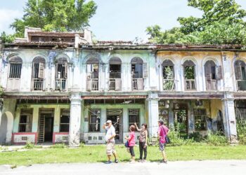 SEKUMPULAN pelancong tertarik melihat keadaan bangunan lama yang dianggarkan berusia lebih 100 tahun di Pekan Papan dekat Batu Gajah, Perak. - UTUSAN/MUHAMAD NAZREEN SYAH MUSTHAFA