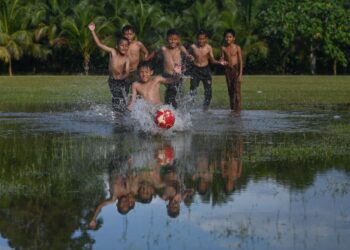 SEKUMPULAN kanak-kanak beriadah dengan bermain bola sepak selepas hujan di Kampung Rawai, Marang, Terengganu, kelmarin. - UTUSAN/PUQTRA HAIRRY