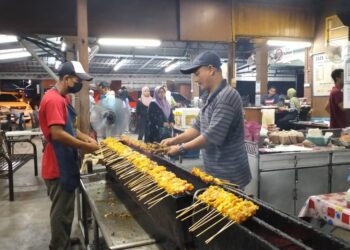 MOHAMAD Faizal Mat Seman (kanan) membakar sate di kedainya Jabi, Besut, semalam.