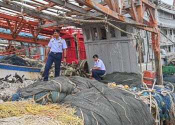 MOHD. Khairulanuar Abd. Majid (kiri) memeriksa salah sebuah bot nelayan asing yang ditahan Maritim Malaysia di Kuala Terengganu, semalam. - UTUSAN/PUQTRA HAIRRY ROSLI