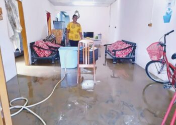 T. Saroja sedang mencuci rumahnya yang dipenuhi lumpur setelah berdepan bencana banjir kilat di Taman Min Terk, Sungai Petani.