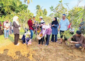 ANAK Allahyarhamah Munirah Abu Bakar menyiram air di pusara ibunya yang selamat dikebumikan di di Tanah Perkuburan Islam Haji Talib di Kampung Paya Tengah, Padang Besar, Perlis, semalam.-UTUSAN/MOHD. HAFIZ ABD. MUTALIB