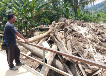 HASLIZAN Abu Hasan menunjukkan sisa-sisa kayu balak yang tersangkut di jambatan berhampiran rumahnya di Kampung Padang Empang, Kupang, Baling. – UTUSAN/NORLIA RAMLI