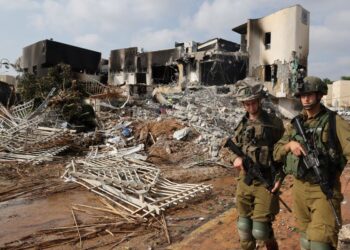 TENTERA Israel berjalan di hadapan sebuah balai polis yang rosak semasa pertempuran dengan pejuang Hamas di Tel Aviv.-AFP