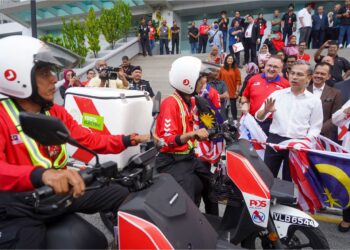 FAHMI Fadzil beramah mesra dengan posmen yang menggunakan kenderaan elektrik pada Majlis Sambutan Hari Pos Sedunia 2023, di Ibu Pejabat Pos Malaysia, Kuala Lumpur, semalam. - UTUSAN/SHIDDIEQIIN ZON