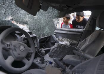 KANAK-KANAK Palestin melihat sebuah kereta yang teruk dihentam bom Israel di Khan Yunis, Gaza. - AFP