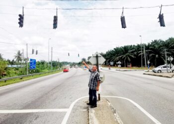 PENDUDUK menunjukkan paras kabel lampu isyarat gantung yang semakin rendah di Jalan Ipoh-Lumut dekat Seri Iskandar di Parit. 
– UTUSAN/AIN SAFRE BIDIN