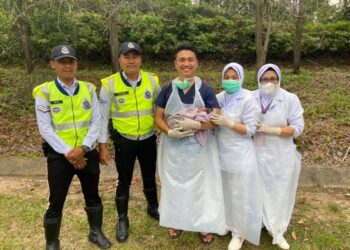 DR. Muhammad Aliff Md. Zaki (tengah) memangku bayi yang selamat dilahirkan dalam treler treler di tepi Lebuhraya Pantai Timur (LPT) menghala ke Kuantan, Pahang, baru-baru ini.