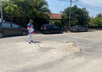 AHMAD SUFIAN Abdul Razak menunjukkan lubang di laluan utama Taman Balok Permai yang dikatakan berpunca dari dikorek untuk membaiki paip air rosak.