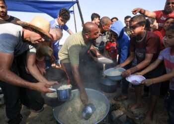 SUKARELAWAN mengagihkan makanan di kem perlindungan sementara bagi penduduk yang hilang tempat tinggal di Khan Yunis, selatan Semenanjung Gaza. - AFP
