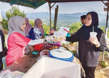 CHE Wan Nurul Huda Che Wan Yusof (kiri) melayan pengunjung yang membeli makanan dan minuman dijualnya di puncak Bukit Jelutong, Kampung Kepah, Hulu Terengganu. –  UTUSAN/NOOR HAYATI MAMAT