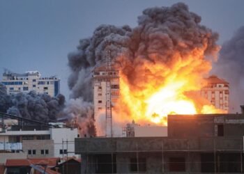 Orang ramai berdiri di atas bumbung melihat api marak dengan asap tebal yang memusnahkan Menara Palestin akibat dibedil pasukan udara Israel di Gaza, Sabtu lalu. – AFP